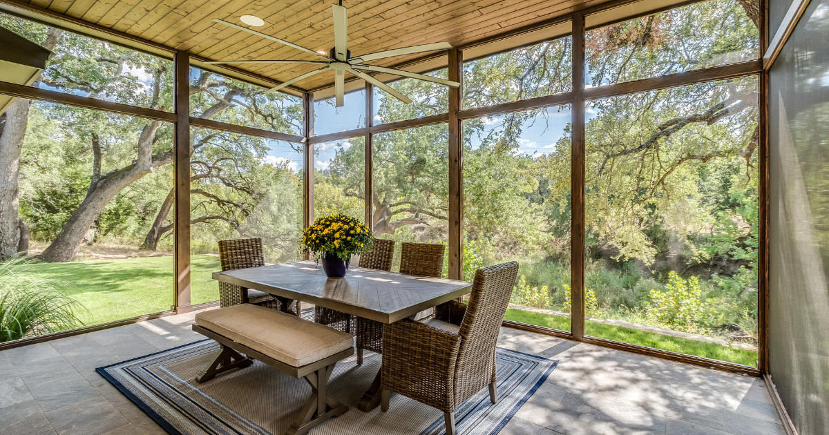 Bright screened-in patio with wood ceiling and dining set, showing how to enclose a patio into a room with natural views.