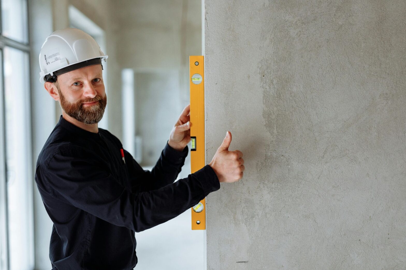Certified professional inspecting a structural wall with a level, reinforcing the value of DIY vs professional contractors for structural wall changes and long-term safety.